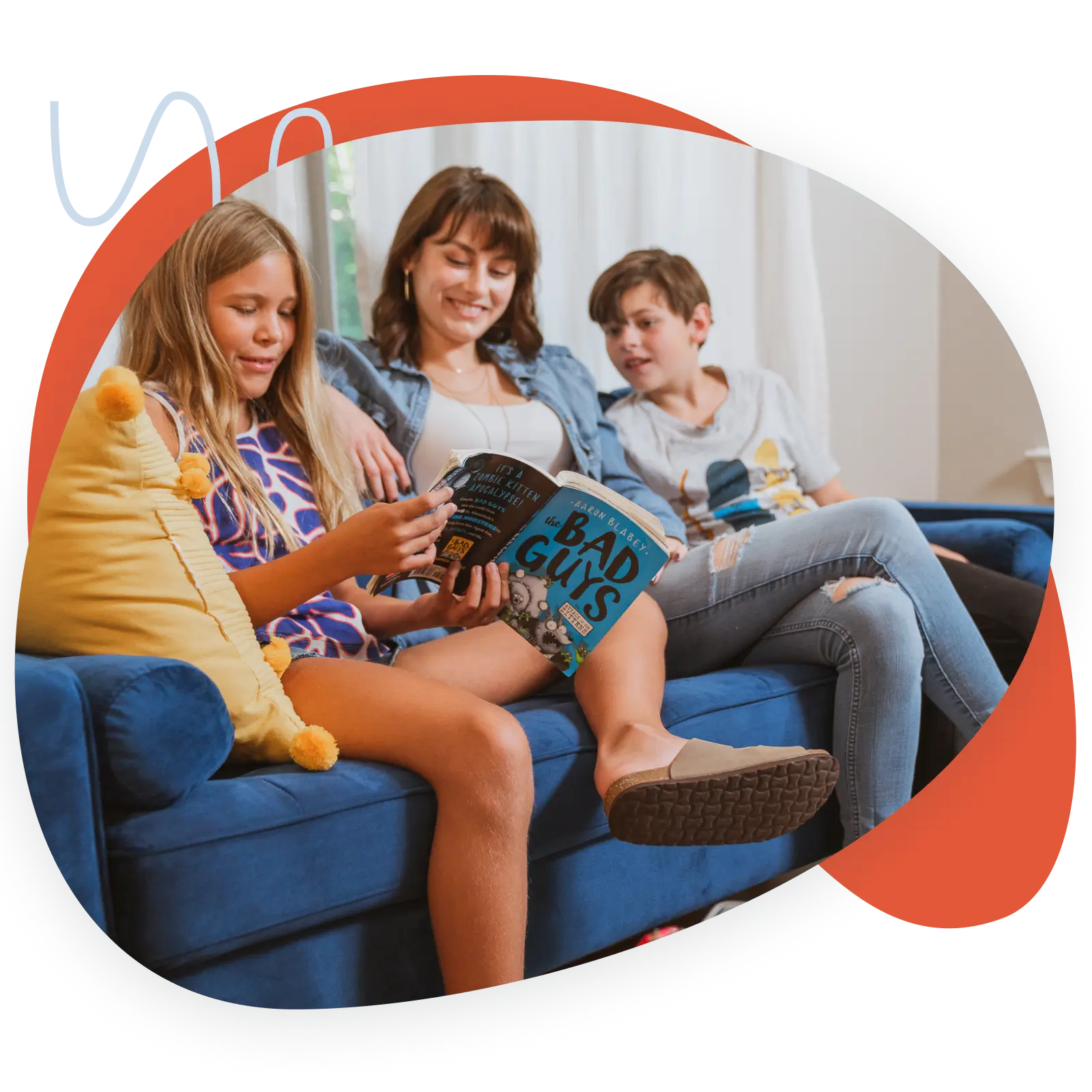 Girl Reading Book On Couch With Mom And Brother